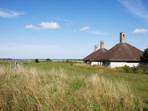 a building in the middle of a field with tall grass at Holiday home on a holiday park in Karrebæksminde in Karrebæksminde