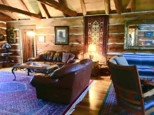 ein Wohnzimmer mit einer Ledercouch und einem Tisch in der Unterkunft Gorgeous Private Cottage Rental in the Black Hills of South Dakota in Nemo