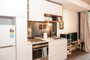 une cuisine avec des armoires blanches et un four à plaques de cuisson dans l'établissement Cosy modern 2BR home in the heart of Melbourne CBD, à Melbourne