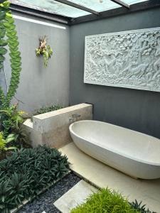 een badkamer met een bad en een muur met een schilderij bij Villa Sage Bali in Darmasaba