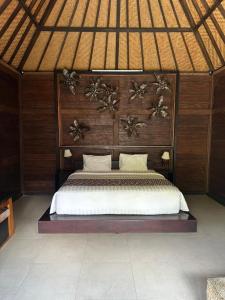 een slaapkamer met een groot bed met een houten hoofdeinde bij Villa Sage Bali in Darmasaba