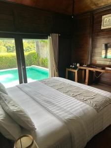 een slaapkamer met een groot bed en een zwembad bij Villa Sage Bali in Darmasaba