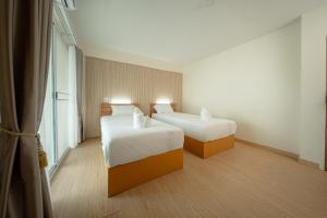 a hotel room with two beds and a window at The Nook Hotel in Chiang Mai