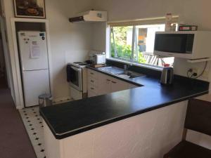 Il comprend une cuisine équipée d'un comptoir noir et d'un réfrigérateur. dans l'établissement Lake Hawea Family Holiday Home, à Lake Hawea