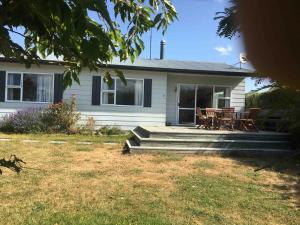 une maison blanche avec une table et des chaises sur la terrasse couverte dans l'établissement Lake Hawea Family Holiday Home, à Lake Hawea