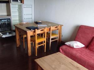 a room with a wooden table and a red couch at Appartement Super Besse - 6 pers, Piscine, Parking, Balcon - FR-1-814-168 in Vassivière +8 photos