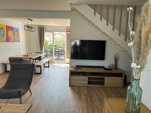 a living room with a flat screen tv and a table at Maison rénovée près de la plage pour 8 personnes avec jardin, wifi et parking - FR-1-194-324 in La Tranche-sur-Mer