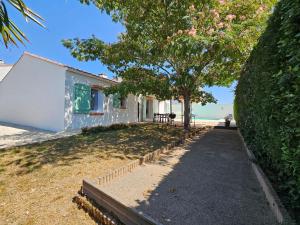 a house on the beach with a tree and a sidewalk at Maison spacieuse avec jardin, animaux admis - FR-1-476-250 in La Faute-sur-Mer