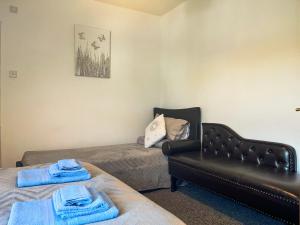 a room with two beds and a leather couch at Sherwood House Apartment 3 in Bakewell