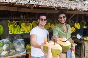 two men holding a coconut in front of a fruit stand at Gilded Palms Villa, Ubud Payangan, Bali in Payangan