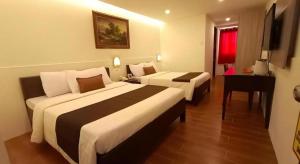 een hotelkamer met twee bedden en een bureau bij Hotel Asuncion in Laoag