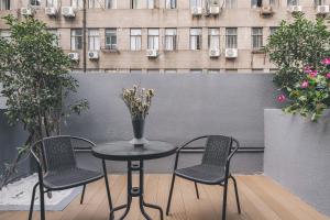 a table with three chairs and a vase with flowers at Atour Hotel Shanghai The Bund East Nanjing Road-Self-service free laundry in Shanghai