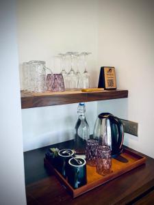een plank met glazen en een waterkoker op een houten dienblad bij Leaf Olu Ella in Yatiyantota