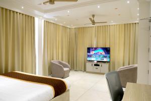um quarto de hotel com uma cama e uma televisão em Munnar Peak Paradise em Devikolam