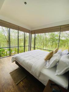 een slaapkamer met een groot bed met een groot raam bij Leaf Olu Ella in Yatiyantota