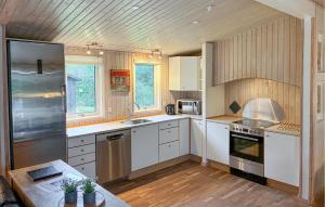 a kitchen with white appliances and wooden walls at Awesome Home In Væggerløse With Sauna in Marielyst