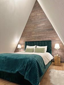 a bedroom with a green bed with a wooden wall at Porumbacu Garden in Porumbacu de Sus