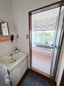 baño con lavabo y bañera con ventana en ist villa 04 Ocean Escape Sleeps 3, en Bizen