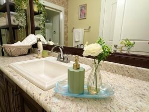a bathroom counter with a sink and a vase with a flower at A Room of One's Own-A perfect getaway by the sea in North Nanaimo in Nanaimo +47 photos