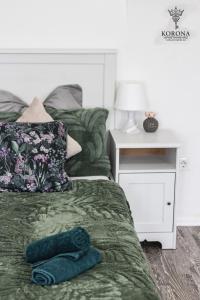 a bedroom with a bed with a green comforter and a night stand at Korona Apartman Székesfehérvár in Székesfehérvár