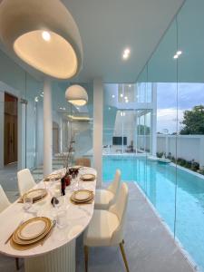 a dining room with a table and a swimming pool at The Pool Space Pool Villa Pattaya A2 พูลวิลล่า in Ban Huai Yai