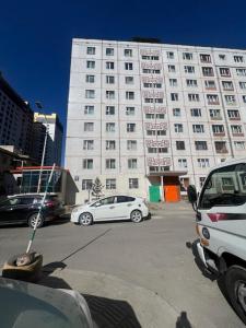 ein weißes Auto, das vor einem großen Gebäude parkt in der Unterkunft Zebra Guest House in Ulaanbaatar