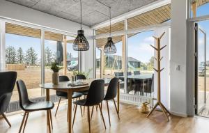 a dining room with a table and chairs and large windows at Cozy Home In Hjørring With Wifi in Hjørring