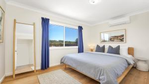 a bedroom with a bed and a large window at Jean's Beach House Accom Holidays in Copacabana
