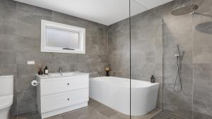a bathroom with a shower and a tub and a sink at Jean's Beach House Accom Holidays in Copacabana