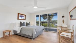 a white bedroom with a bed and a balcony at Jean's Beach House Accom Holidays in Copacabana +7 photos