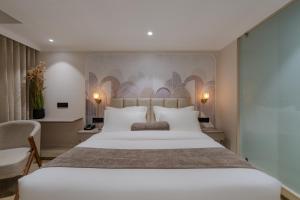 a bedroom with a large white bed and a chair at Hotel The Grand Suites in Ahmedabad +52 photos