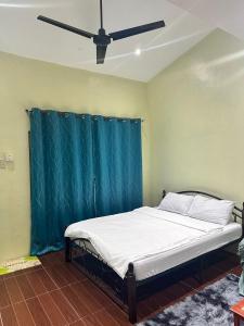 een bed in een kamer met een plafondventilator bij SJ Vistacation in Tanza