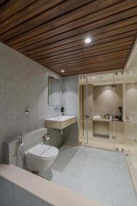 a bathroom with a toilet and a sink and a shower at Hotel The Grand Suites in Ahmedabad