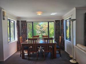 a dining room with a table and chairs and windows at Fisherman's Friend - a spacious family beach home in Pohara