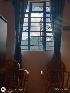 een raam met twee stoelen ervoor bij Mountain Paradise Homestay BATASIA LOOP in Darjeeling