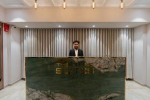 a man standing behind a table in a room at Hotel The Grand Suites in Ahmedabad