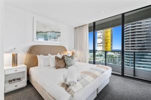 a bedroom with a white bed and a large window at Luxurious 2-Bed Designer Retreat at Oracle Resort in Gold Coast