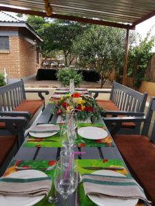 una mesa larga con platos y flores. en Tlou- Sejie Hotel, en Palapye