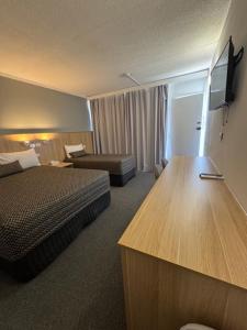 a hotel room with a bedroom with a bed and a couch at The Sands Motel Adelaide in Adelaide