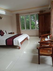 une chambre avec un lit, une table et des fenêtres dans l'établissement Khách Sạn Thành Loan 2, à Nà Phia