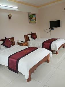 une chambre d'hôtel avec deux lits et une télévision dans l'établissement Khách Sạn Thành Loan 2, à Nà Phia