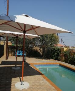 Una sombrilla blanca junto a una piscina. en Tlou- Sejie Hotel, en Palapye