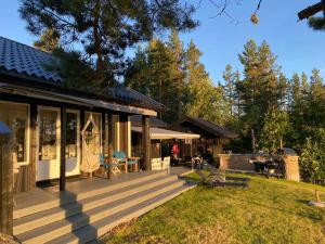 a house with a large wooden deck with a yard at Norwegian Cabin Vibes With View In Vegårshei in Gjerstad
