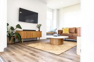 a living room with a couch and a tv on a wall at Discover - Ebenezer Bicheno in Bicheno