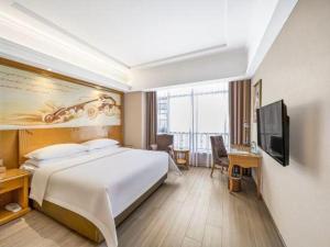 a hotel room with a bed and a flat screen tv at Vienna Hotel Anhui Xuancheng High-Speed Railway Station in Xuancheng