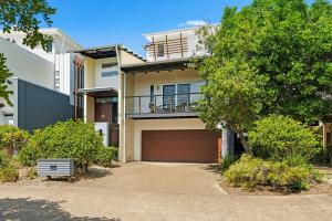 a white house with a garage and a tree at Family Beach House at Twin Waters Resort in Twin Waters