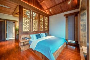 a bedroom with a bed with blue sheets and wooden floors at Sanctum Peaks in Zhangjiajie +173 photos