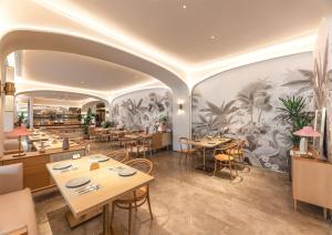 a restaurant with tables and chairs and a mural of palm trees at Mercure Hotel in Xi'an