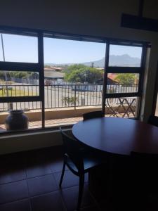 Una mesa y sillas frente a una ventana con vistas en 4Th On Boundary, en Gordonʼs Bay 4 fotos más