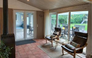a living room with chairs and a porch with sliding glass doors at Awesome Home In Væggerløse With Sauna in Marielyst